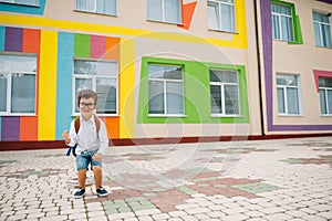 Back to school. Happy smiling boy in glasses is going to school for the first time. Child with backpack and book