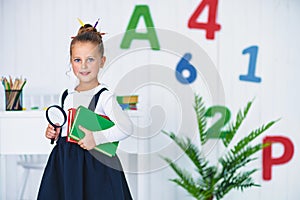 Back to school. Happy smiling pupil at the desk. Child in the class room with pencils, books. Kid girl from primary