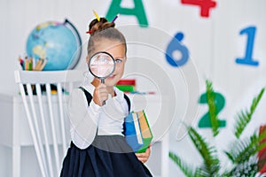 Back to school. Happy smiling pupil at the desk. Child in the class room with pencils, books. Kid girl from primary