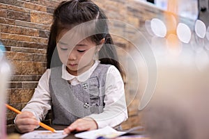 Back to school. Happy smiling pupil drawing at the desk. Cute little preschooler child drawing at home. Kid girl drawing with penc