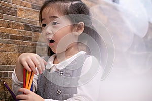 Back to school. Happy smiling pupil drawing at the desk. Cute little preschooler child drawing at home. Kid girl drawing with penc