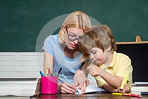 Back to school and happy time. Teacher helping kids with their homework in classroom at school. Talented child