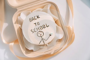 Back to school inscription on a white round cake in a gift container with a ribbon