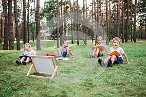 Back to school. Kindergarten and elementary scholars sitting on grass at open-air class