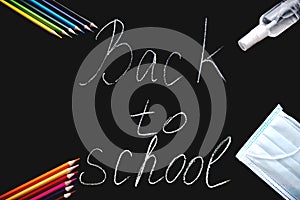 `Back to School` lettering among school supplies and personal protective equipment.
