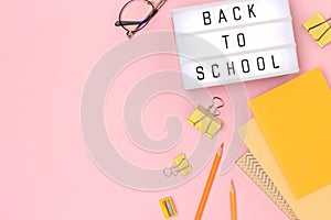 Back to school. Lightbox with letters and stationery on a pink background.