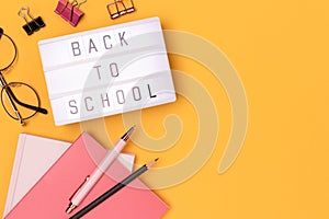 Back to school. Lightbox with letters and stationery on a yellow background.