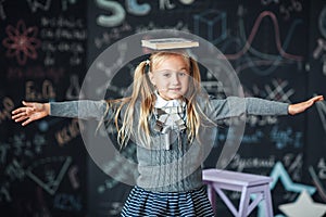 Back to school. little blond girl in school uniform child from elementary school keeps a books on her head. education. child with