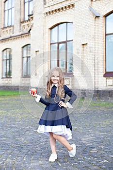 Back to school. A little girl of preschool age stands with an apple on her first day at school or kindergarten. little schoolgirl