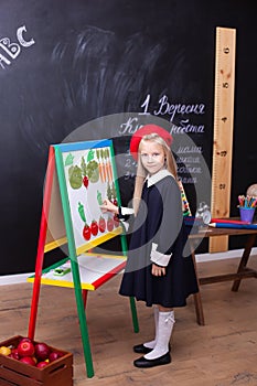 Back to school! little girl is standing near the school board.  On the blackboard in Ukrainian is written `1st of September. Class