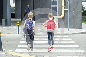 Back to school. Little pedestrians with backpacks walk to school and cross road at crosswalk