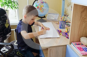 Back to school. Little tired boy doing homework at home with backpack full of books, pencils. Kid is drawing, writing and painting