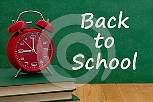 Back to School message with alarm clock on books with a chalkboard