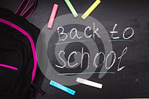 Back to school message on Blackboard inscribed with colorful chalk for background. Backpack.