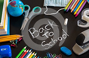 Back to School message on chalkboard with school supplies