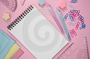Back to school. Mockup. School composition with blank notepad and stationery on a pink background. Flatlay. Top view. Copy space