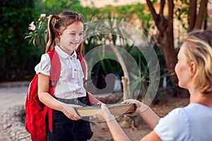 Back to school. Mother giving book to her child before going to school