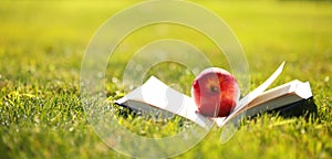 Back to School. Open Book and Apple on Grass.