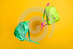 Back to school. Pair two colorful flying rucksacks thrown up by classmates groupmates summer holidays begin yellow