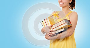 Back to school. Portrait of a happy smiling woman holding a stack of books. Blue background. Copy space. Concept of education and