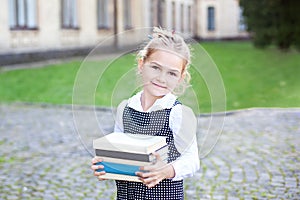 Back to school. Portrait of a schoolgirl with books, textbooks on the background of the school. Education concept. Preschool educa