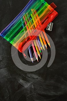 Back to school. Rainbow pencil case with school supplies for student. Black background. Copy space