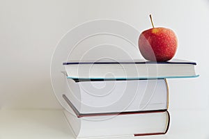 Back to school. Red apple next to books on a white background