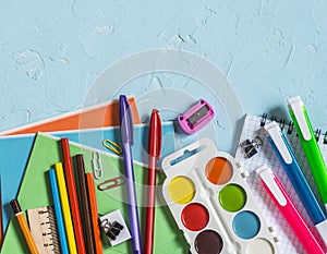 Back to school. School accessories - notebooks, pens, pencils, paint on a blue background, top view. Education concept. Flat lay