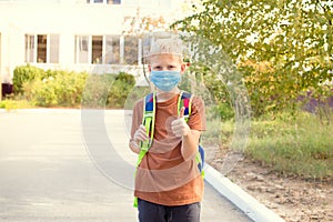 Back to school. School-age boy with a protective medical mask on her on his face with a school backpack. New school year in 2020.C