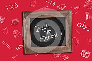 Back to school. School supplies at the table. Red background. Chalkboard