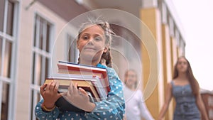 back to school. schoolgirl carries textbooks books go to school behind with a backpack holding hands. kid education