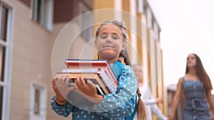 back to school. schoolgirl carries textbooks books go to school behind with a backpack holding hands. kid education