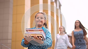 back to school. schoolgirl carries textbooks books go to school behind with a backpack holding hands. kid education