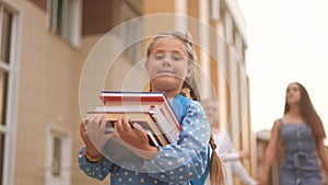 back to school. schoolgirl carries textbooks books go to school behind with a backpack holding hands. kid education