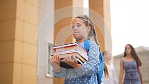 back to school. schoolgirl carries textbooks books go to school behind with a backpack holding hands. kid education