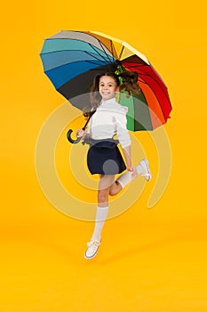 Back to school on September 1. Adorable schoolgirl with rainbow umbrella on September 1 on yellow background. Small