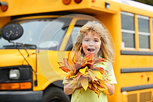 Back to school in september. Autumn child near school bus. Fall foliage. Schooler school boy in fall autumn park.