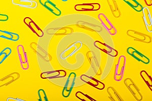 Back to school shopping concept. School office supplies paper clips on yellow background. Flat lay top view, copy space.