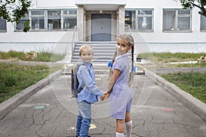 Back to school. Siblings with backpacks staying near school doors before their first offline day