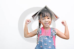 Back to school. Smiling little girl carrying a backpack holding books on her head looking at the camera on a white background with