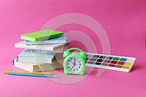 Back to school, stationery, alarm clock, stack of books on bright background