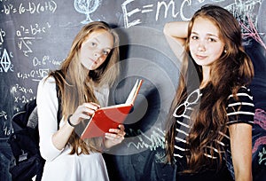 Back to school after summer vacations, two teen real girls in classroom with blackboard painted together