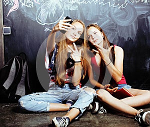 Back to school after summer vacations, two teen real girls in classroom with blackboard painted together, lifestyle