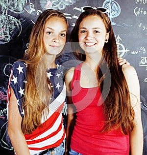 Back to school after summer vacations, two teen real girls in classroom with blackboard painted together, lifestyle real