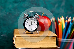 Back to school supplies. Books and red apple on green background