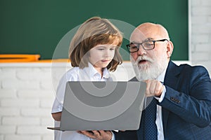 Back to school. Teacher and child with laptop. Online education and learning concept. Schoolboy in classroom. Old