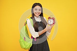Back to school. Teenage school girl with backpack hold clock alarm, time to learn. Schoolgirl on isolated yellow