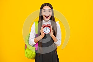Back to school. Teenager school girl with backpack hold clock alarm, time to learn. School children on isolated yellow