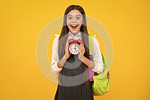 Back to school. Teenager school girl with backpack hold clock alarm, time to learn. School children on  yellow