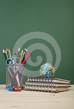 Back to school template with stationeries and books on table over green photo